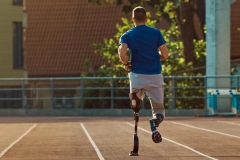 Athletic Disabled Fit Man with Prosthetic Running Blades is Training on a Outdoors Stadium on a Sunny Afternoon.