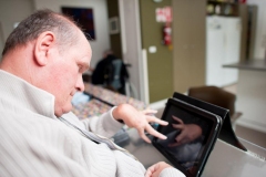 Mature aged man with a disability operating touchscreen computer.