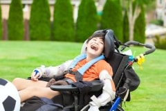 Ten year old disabled boy in wheelchair playing with soccer ball at park