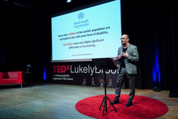 Clive giving his Ted Talk. Behind him, a screen says 