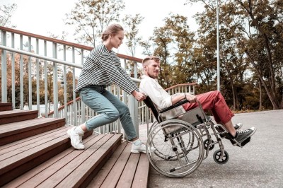 Young woman frowning while struggling to carry her invalid friend upstairs